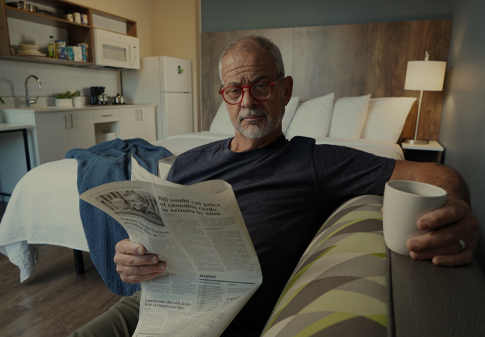 senior man lounging while reading newspaper